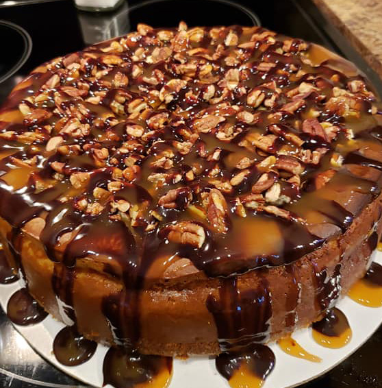 Turtle cheesecake topped with caramel, chocolate, and pecans.
